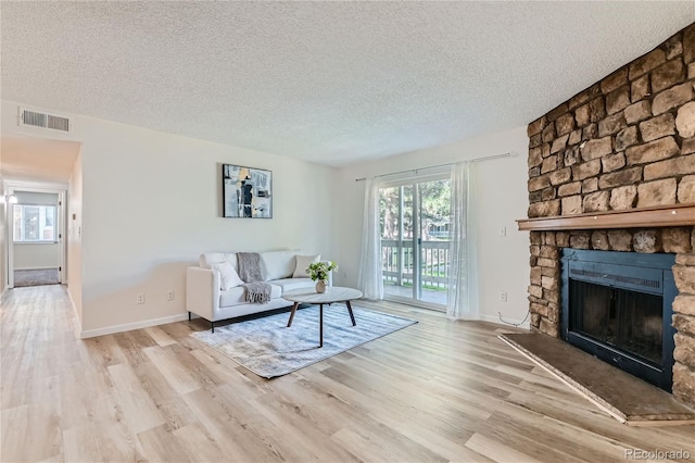 living room featuring a fireplace, a textured ceiling, and light hardwood / wood-style flooring