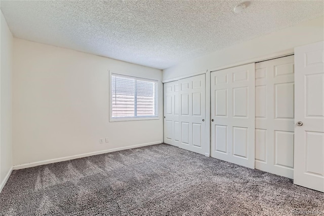 unfurnished bedroom featuring multiple closets, carpet, and a textured ceiling