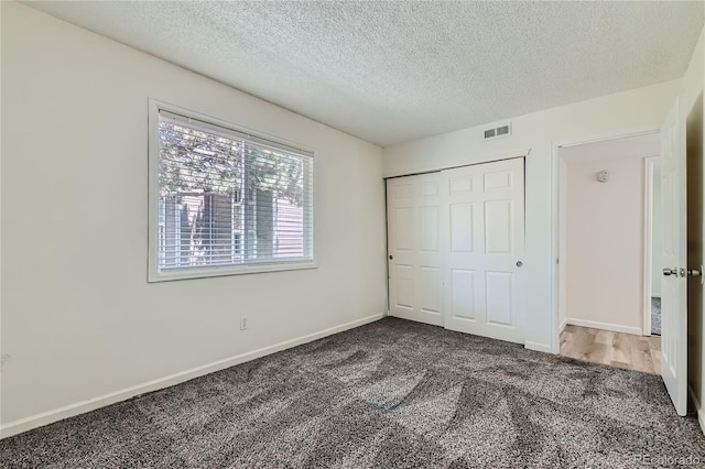 unfurnished bedroom with carpet floors, a textured ceiling, and a closet