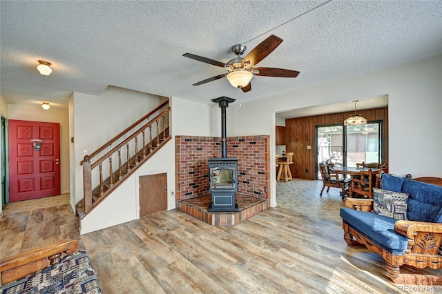 living room featuring hardwood / wood-style floors, a wood stove, a textured ceiling, and wooden walls