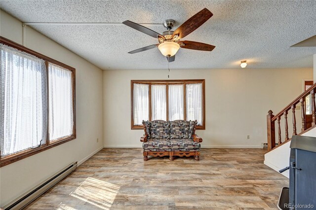 sitting room with a baseboard radiator, light hardwood / wood-style flooring, plenty of natural light, and ceiling fan