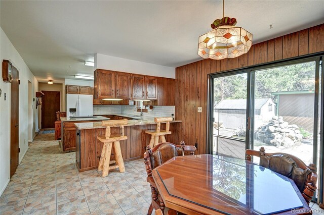 dining space with light tile patterned floors and wooden walls