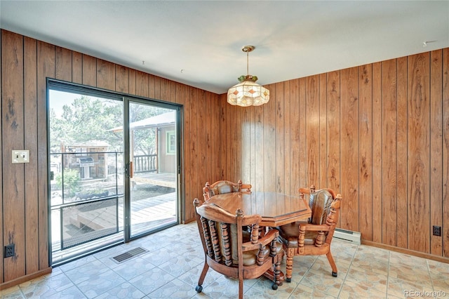 dining area featuring baseboard heating and wood walls