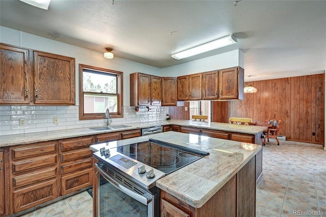 kitchen featuring backsplash, sink, wooden walls, appliances with stainless steel finishes, and a kitchen island