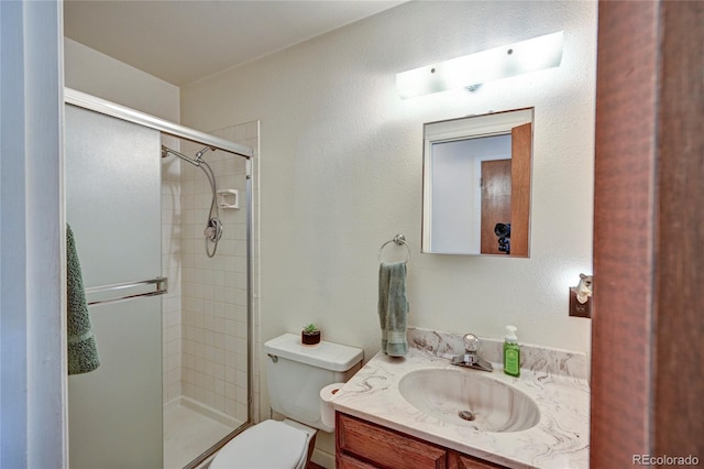 bathroom with a shower with door, vanity, and toilet