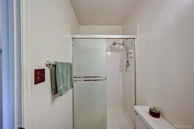 bathroom with toilet and a shower with shower door