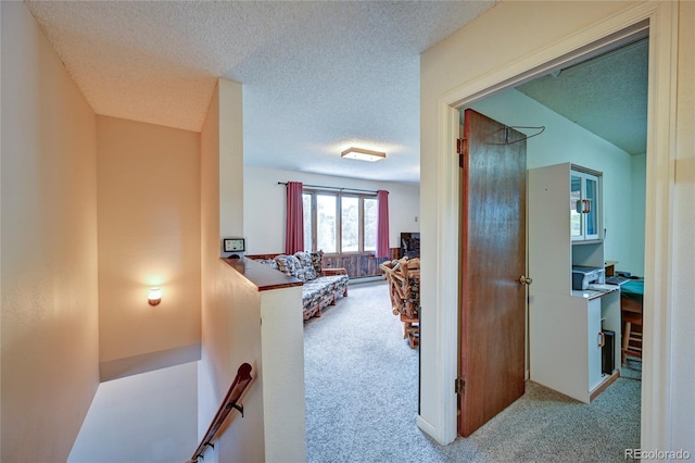 hallway with a textured ceiling and light colored carpet