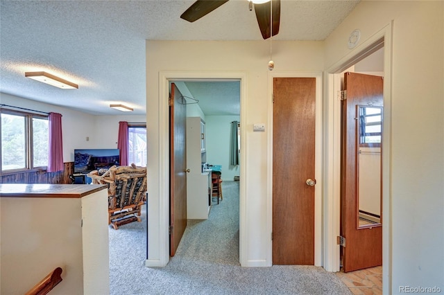 hall featuring light carpet and a textured ceiling