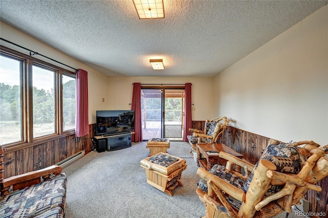 living room featuring wood walls, carpet floors, a textured ceiling, and baseboard heating