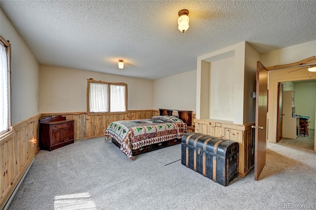 bedroom with a textured ceiling, light colored carpet, and a baseboard radiator