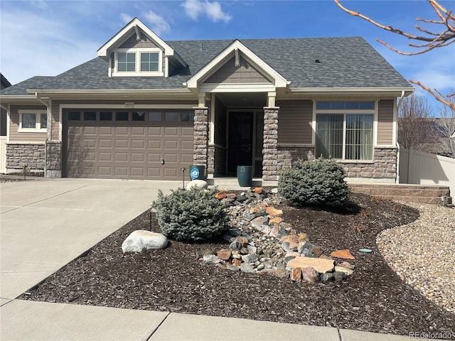 craftsman-style house with a shingled roof, stone siding, fence, and concrete driveway