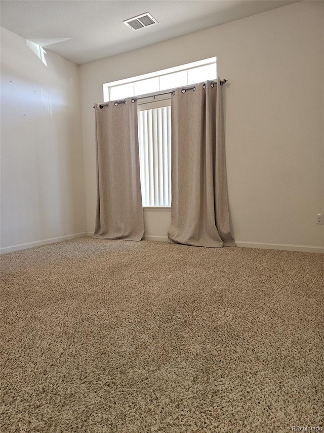 spare room featuring carpet floors, visible vents, and baseboards