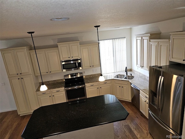 kitchen with appliances with stainless steel finishes, a sink, cream cabinets, and dark wood-style floors