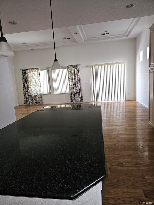 empty room with a raised ceiling, wood finished floors, and visible vents