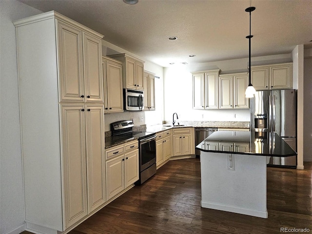 kitchen with appliances with stainless steel finishes, dark wood-type flooring, a sink, and cream cabinets