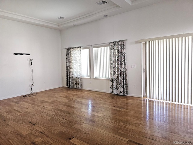 unfurnished room with a tray ceiling, baseboards, and wood finished floors