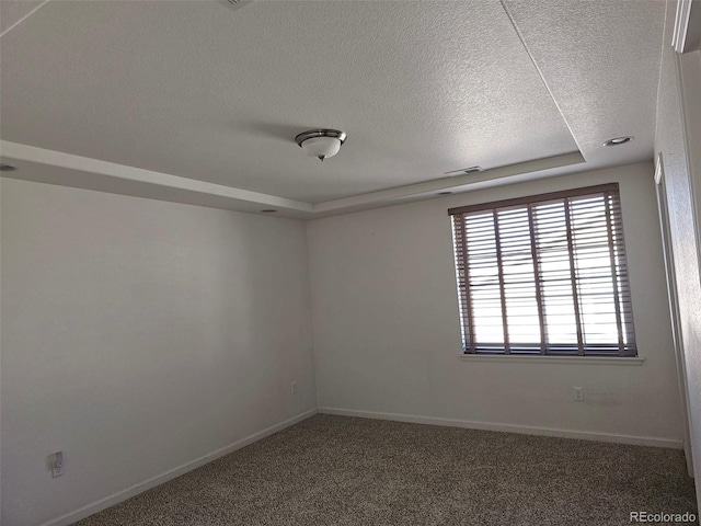 carpeted spare room with visible vents, baseboards, and a textured ceiling