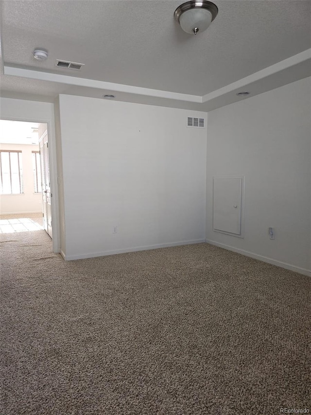 empty room featuring baseboards, carpet, visible vents, and a textured ceiling