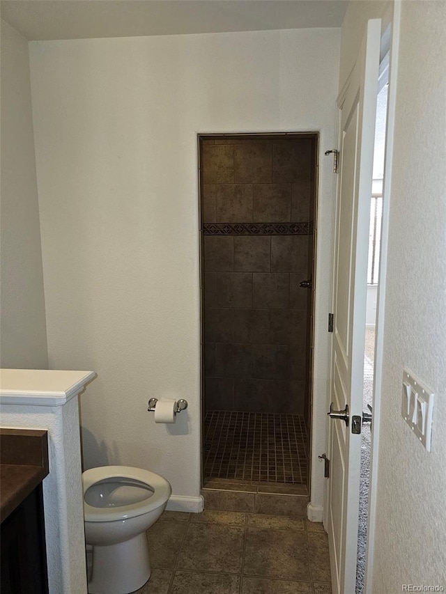 bathroom featuring tile patterned flooring, toilet, vanity, baseboards, and a stall shower