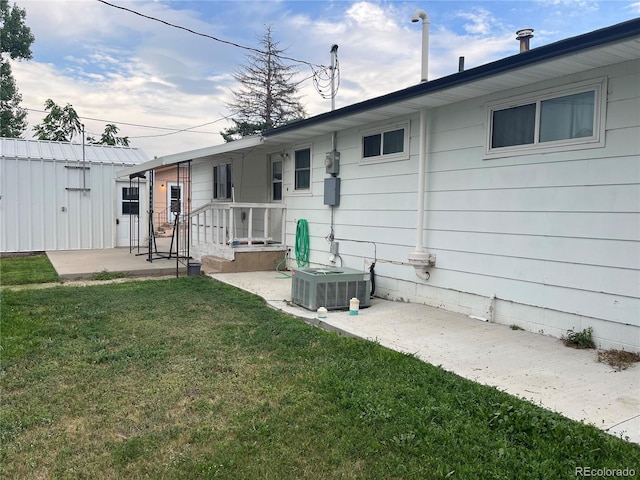 rear view of property featuring a patio, central AC unit, and a lawn