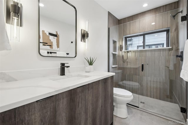 bathroom with vanity, toilet, and a shower with door