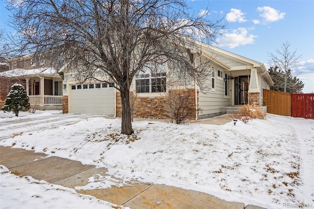 view of front of home featuring a garage, stone siding, and fence