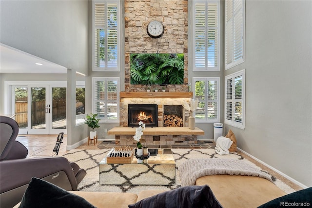 tiled living room featuring french doors, baseboards, a stone fireplace, and a high ceiling