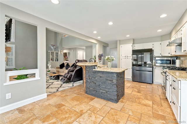 kitchen featuring stone tile floors, recessed lighting, stainless steel appliances, white cabinets, and light stone countertops