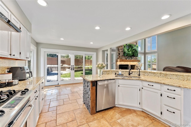 kitchen with recessed lighting, a sink, white cabinetry, appliances with stainless steel finishes, and stone tile flooring