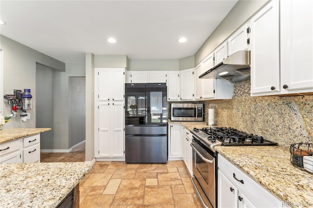 kitchen featuring light stone countertops, stone tile floors, under cabinet range hood, stainless steel appliances, and decorative backsplash