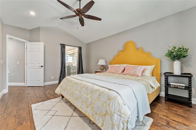 bedroom with ceiling fan, ensuite bathroom, hardwood / wood-style flooring, baseboards, and vaulted ceiling