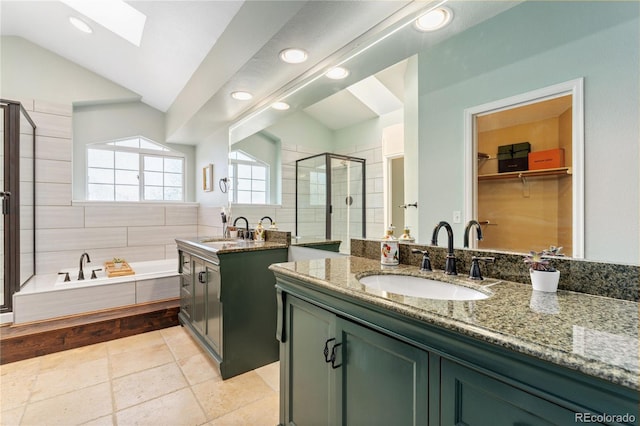 bathroom with a garden tub, vaulted ceiling with skylight, a sink, and a shower stall