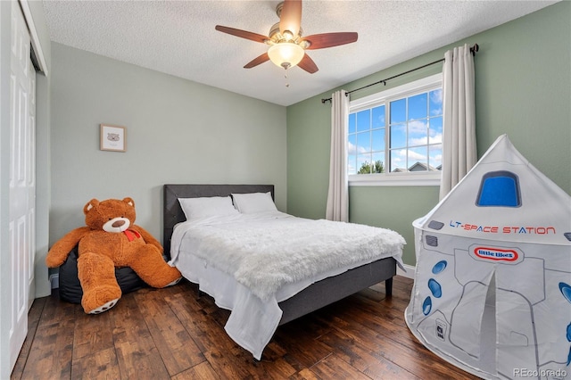 bedroom with a textured ceiling, a closet, wood-type flooring, and a ceiling fan