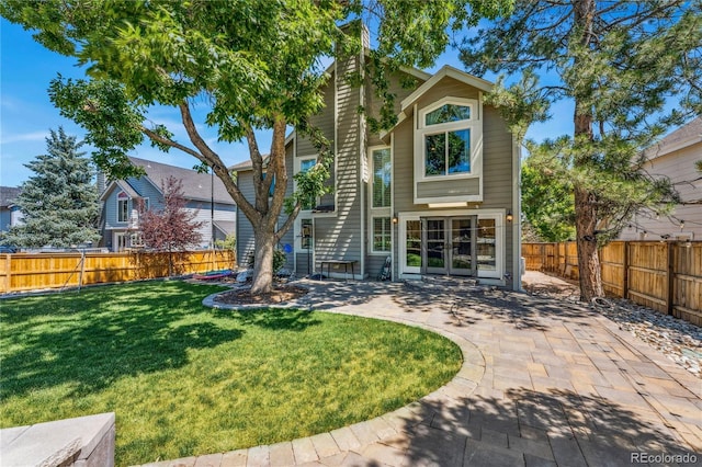 back of property with a yard, a patio area, and a fenced backyard