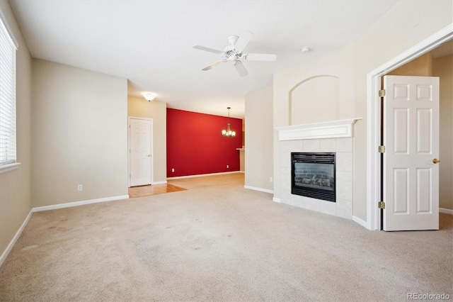 unfurnished living room with ceiling fan with notable chandelier, carpet floors, and a tile fireplace