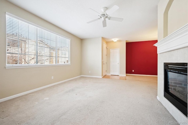 unfurnished living room featuring a tiled fireplace, light colored carpet, and ceiling fan