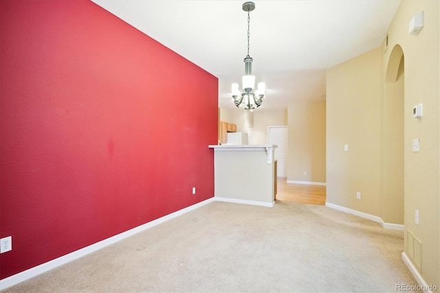 carpeted empty room featuring an inviting chandelier