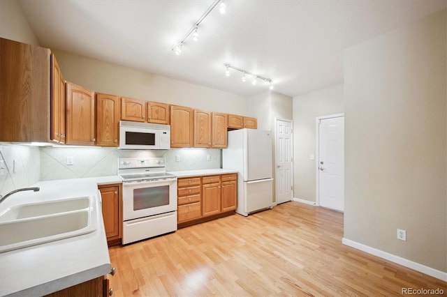 kitchen featuring tasteful backsplash, white appliances, light hardwood / wood-style floors, and sink