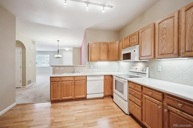 kitchen with sink, tasteful backsplash, decorative light fixtures, white appliances, and light hardwood / wood-style floors