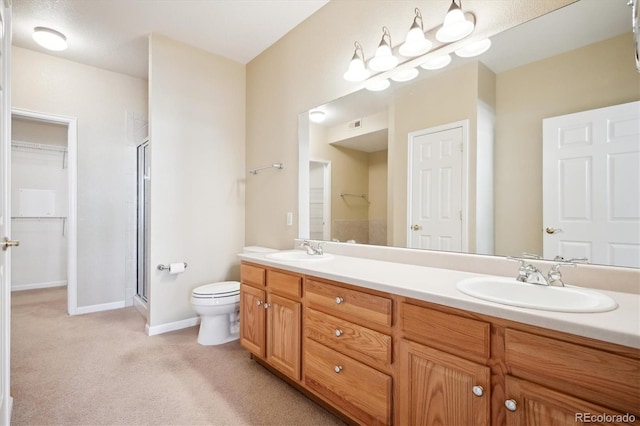 bathroom featuring vanity, a shower with door, and toilet