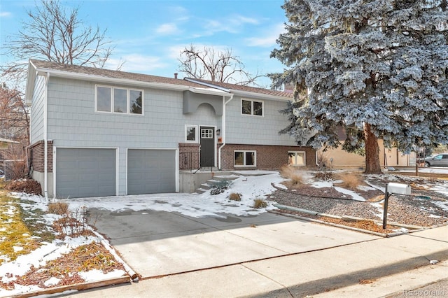 bi-level home featuring driveway, an attached garage, and brick siding