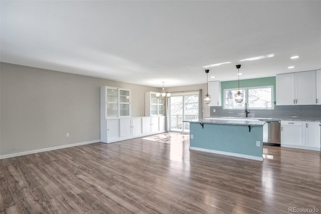 kitchen featuring a center island, decorative light fixtures, tasteful backsplash, stainless steel dishwasher, and white cabinetry