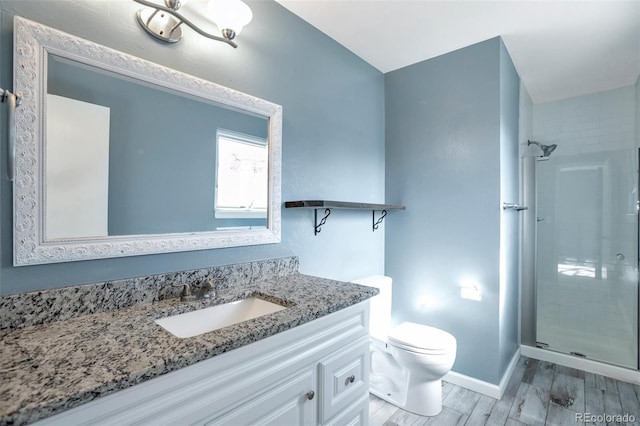 full bathroom with a stall shower, baseboards, toilet, wood finished floors, and vanity