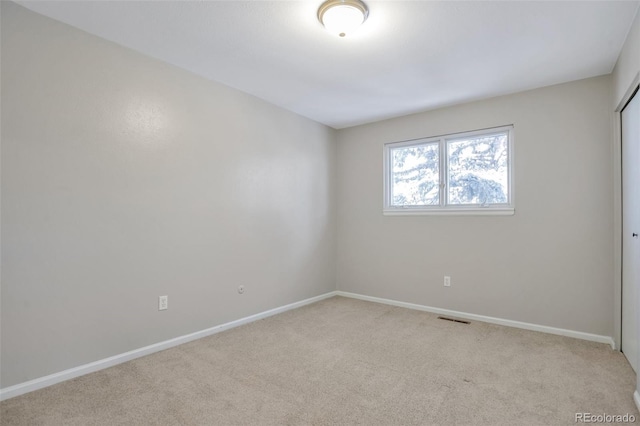 spare room featuring light carpet, visible vents, and baseboards