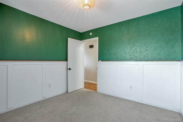 unfurnished room with wainscoting and light colored carpet