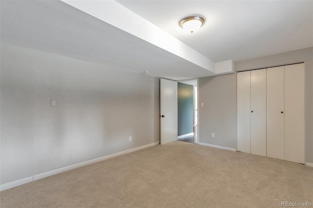 unfurnished bedroom with a closet, light carpet, and baseboards