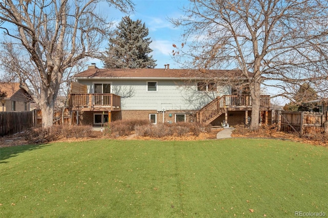 rear view of property featuring a lawn, fence, a deck, and stairs