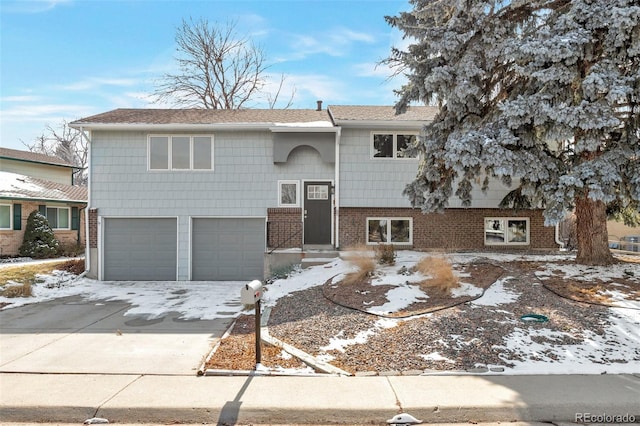 raised ranch with an attached garage, concrete driveway, and brick siding