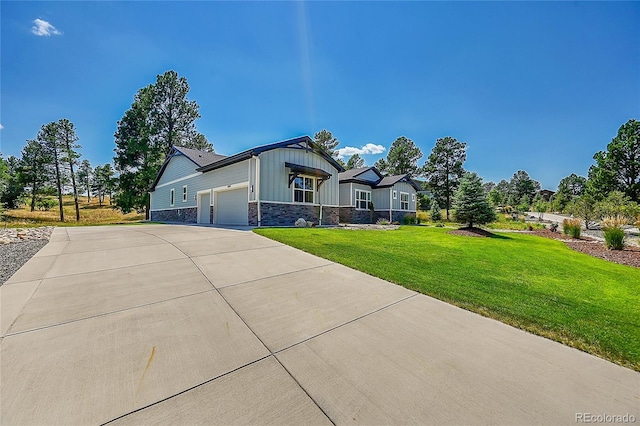 view of front facade featuring board and batten siding, an attached garage, stone siding, driveway, and a front yard