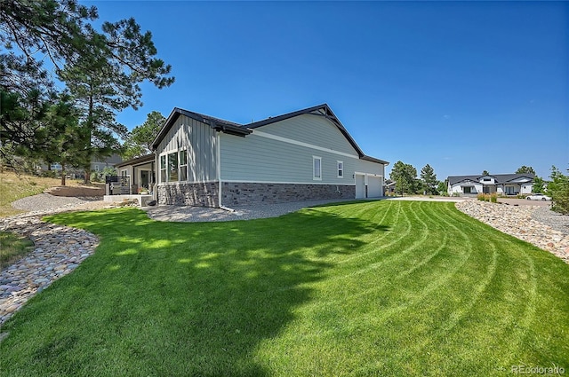 view of property exterior featuring stone siding, a lawn, an attached garage, and board and batten siding